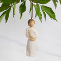 Front view: Dated Ornament of figure holding pierced gold-leaf wreath of hearts. 2024 written on wreath; loop and hook in head