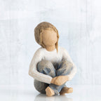 Little girl figurine sitting with legs crossed - faceless - wearing white shirt and blue jeans