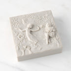 Closed white resin box; lid carved with figural and organic imagery