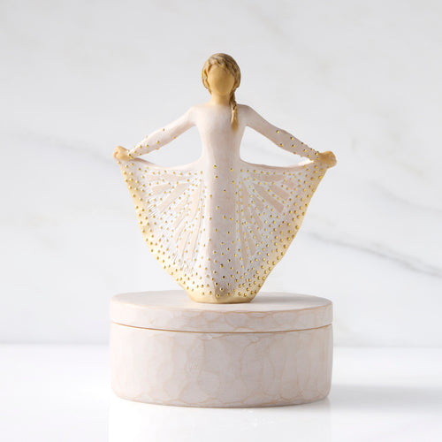 Front view: oval resin box, with 3-D figure in cream and gold carved dress atop lid