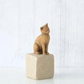 Golden cat figurine sitting on white rock