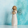 Willow Tree With affection, 5”h hand-painted standing resin angel figure, in cream dress with wire wings, holding gray cat, in front of cerulean painting