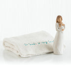 Brown haired woman figurine wearing white holding baby - next to white towel