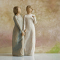 Willow Tree My sister, my friend, 8.5”h hand-painted figure of two females standing next to each other, arms/hands connected, one in cream dress, one in blue/gray dress, in front of dusty pink painting