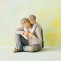 Willow Tree That's my Dad, 4”h hand-painted resin figure of seated man with younger boy leaning over his back, both in neutral clothes, in front of light yellow painting