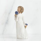 Brunette girl figurine in white dress holding blue flowers