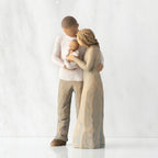 Left view of standing couple, woman has lighter skin and hair; man has darker skin and hair, holding a baby between them.