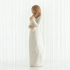 Side view of brunette girl figurine in white dress holding baby