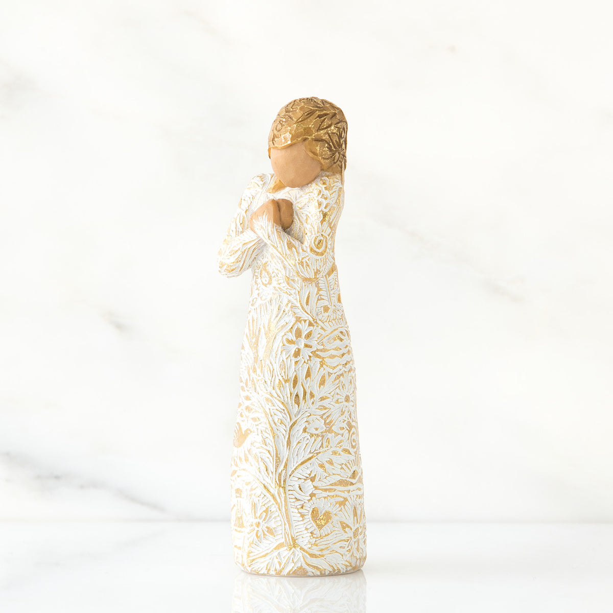 Gold haired woman in white/gold dress facing forward with arms to her chest