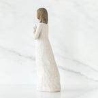 Brunette girl figurine in white dress facing away from camera