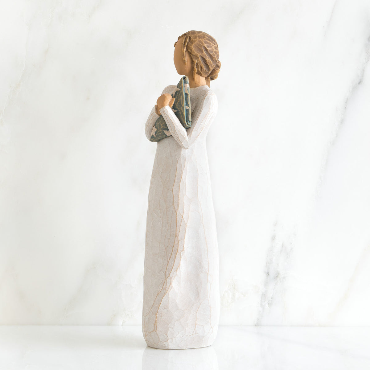 Side view of brunette girl figurine in white dress holding triangle figurine
