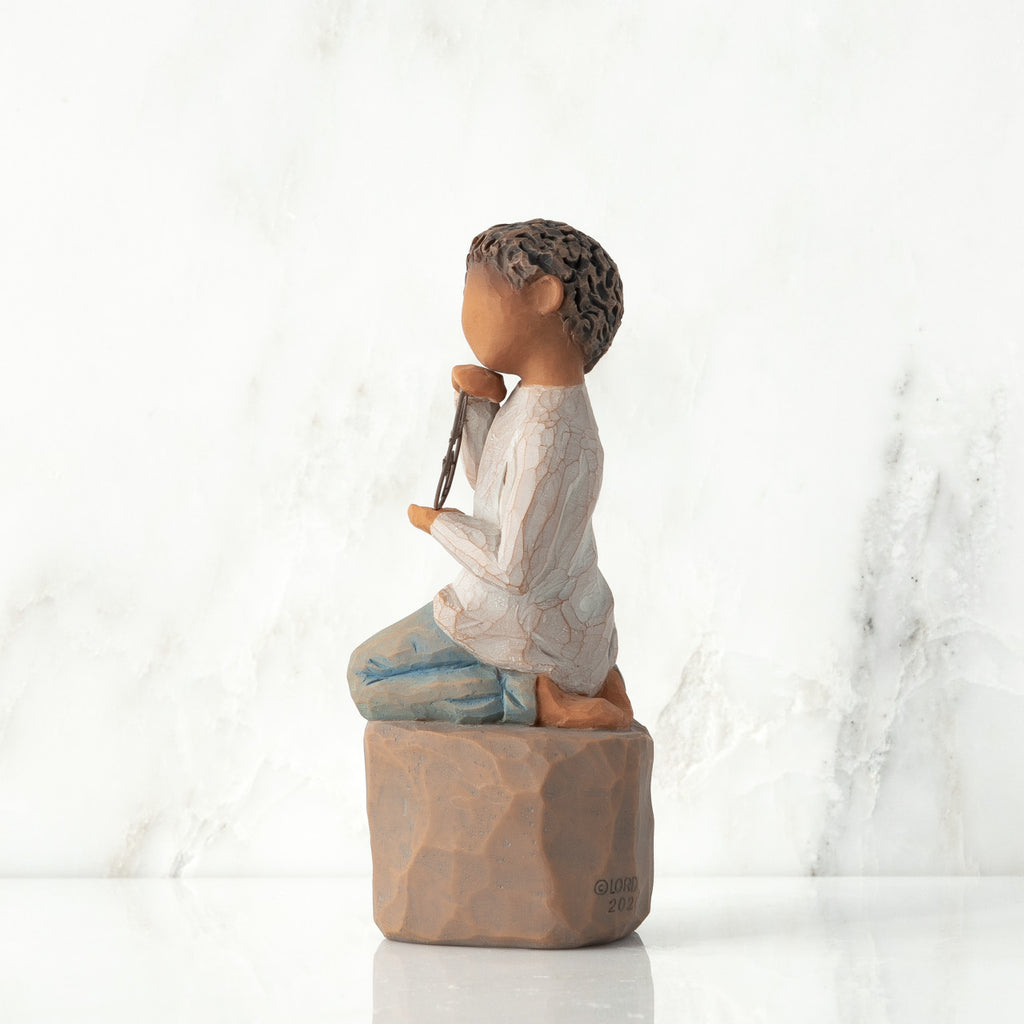 Left view: Figure of darker-skin child, kneeling on rock, holding wire circle with ‘love you’ written in wire