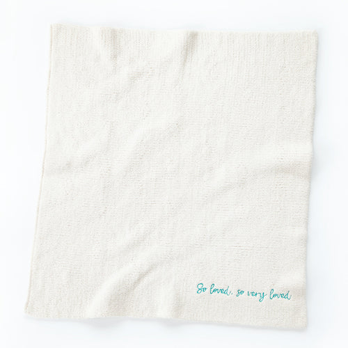 Overview of white towel with 'so loved, so very loved' in light blue in the right corner
