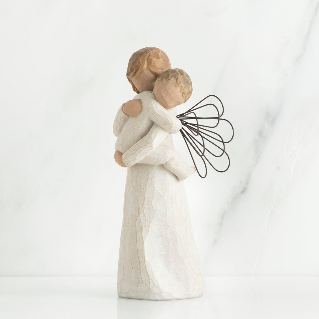 Angel figurine with black wire wings  in white holding baby in her arms