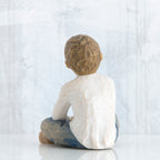 Back view of young brunette boy in white shirt and blue jeans sitting down
