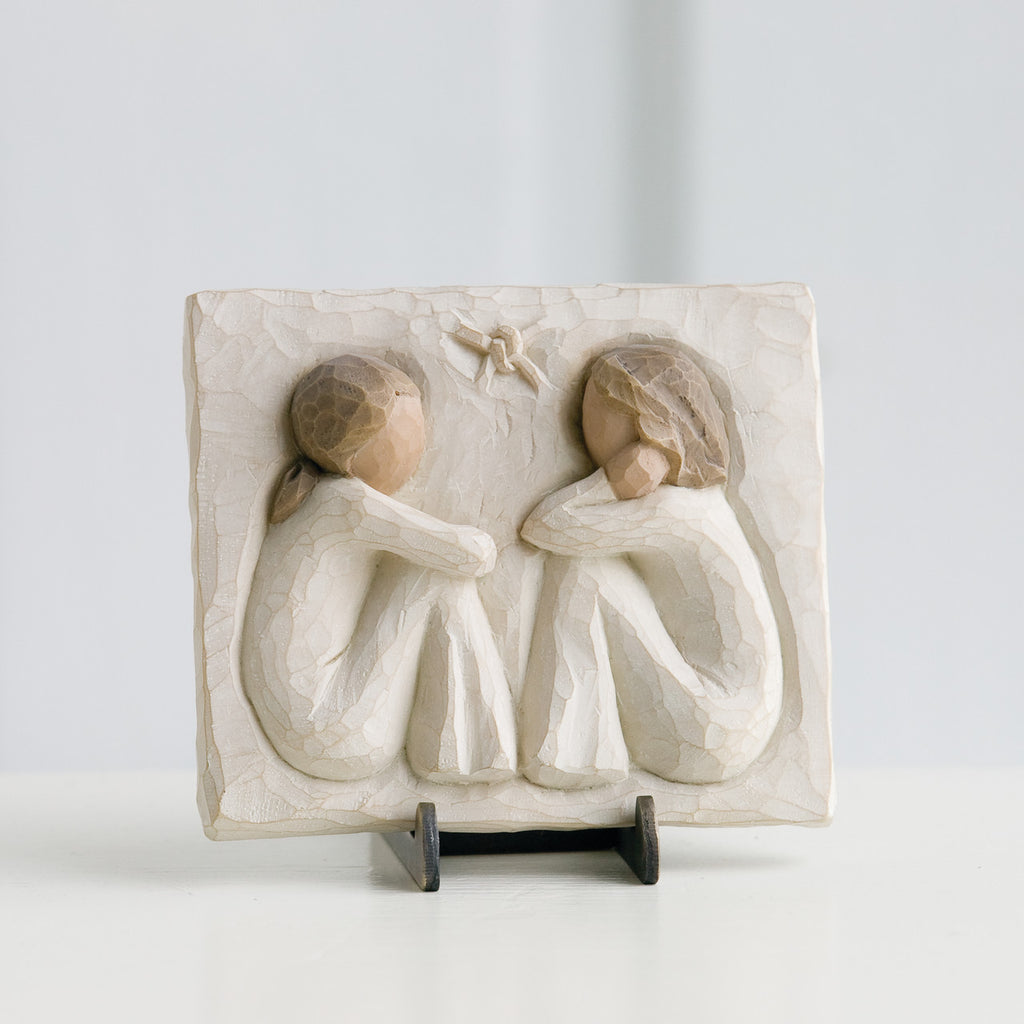 Small cream rectangle plaque with two girl figurines carved in sitting down facing one another