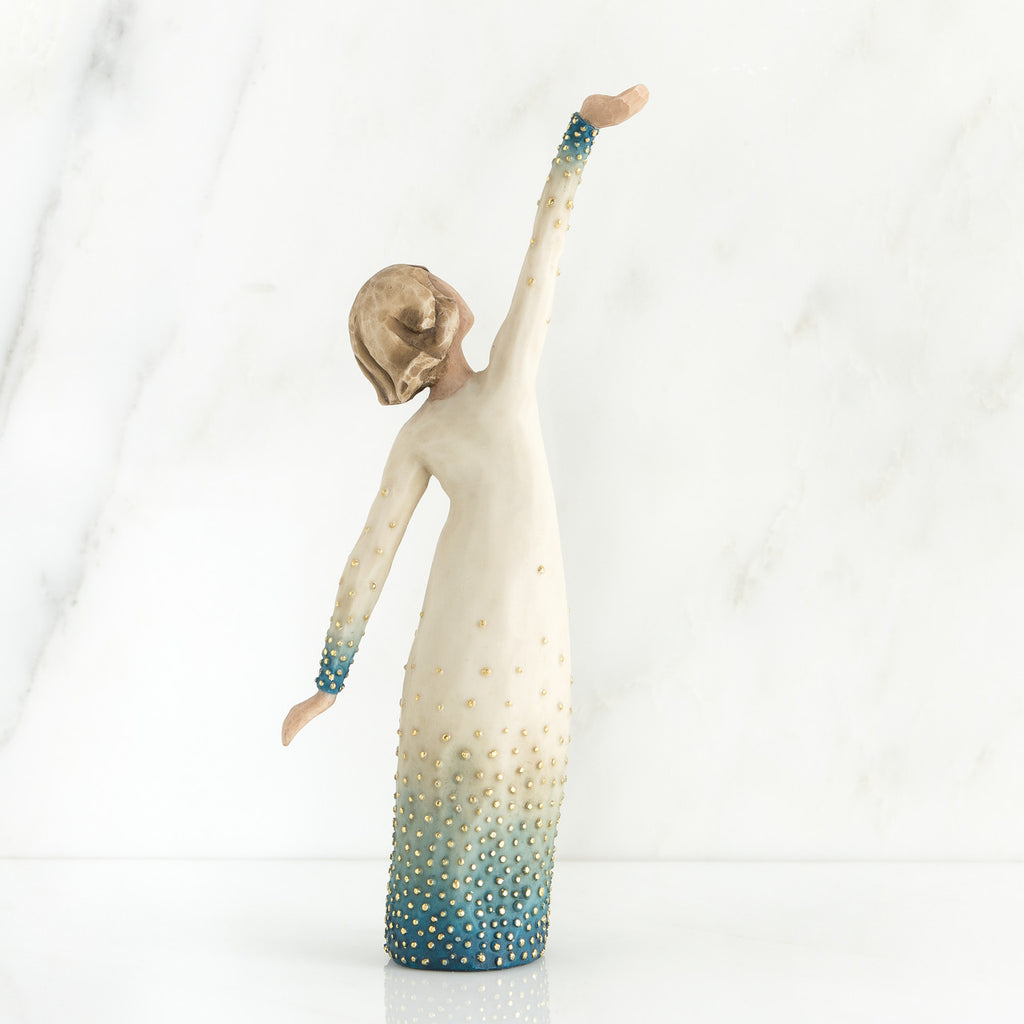 Girl figurine in white dress with blue bottom facing the back with her arms spread
