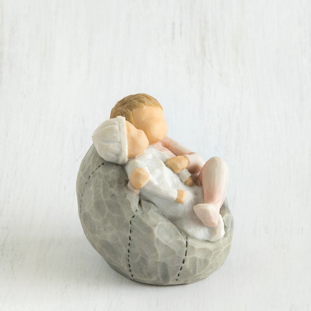 Small baby figurines laying on grey bean bag figurine