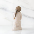 Back view of kneeling female figure in cream dress, with wire butterfly on extended hands