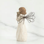 Back view of brunette angel figurine in white dress holding grey cat