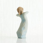 Back view of girl figurine in blue dress standing with her arms up