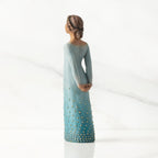 Facing left/back: Darker-skin figure, arms clasped behind back, hair and deep blue ombré garment dotted with gold leaf