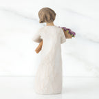 Standing figure with short brown hair wearing long cream dress holding large bouquet of purple tulips, facing back