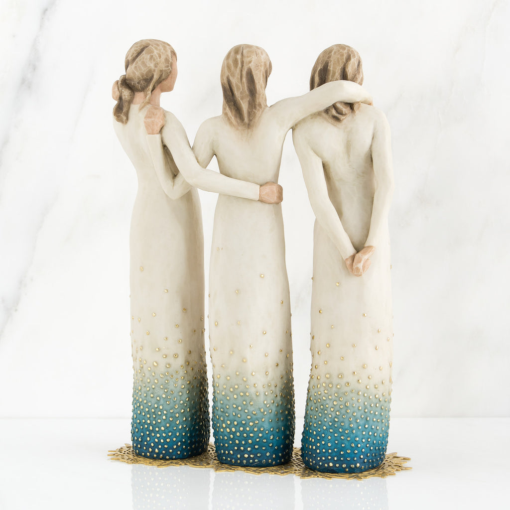 Set of three woman figurines wearing white/blue dresses facing the back with arms around each other
