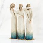 Set of three woman figurines wearing white/blue dresses facing the back with arms around each other