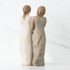 Back view of two woman figurines - one is in white, one is in brown