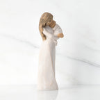 Side view of brunette woman figurine in white dress holding swaddled baby