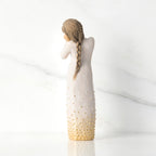 Back view, standing figure in cream dress, showing long braid, and gold-leaf dot detail on dress and hair