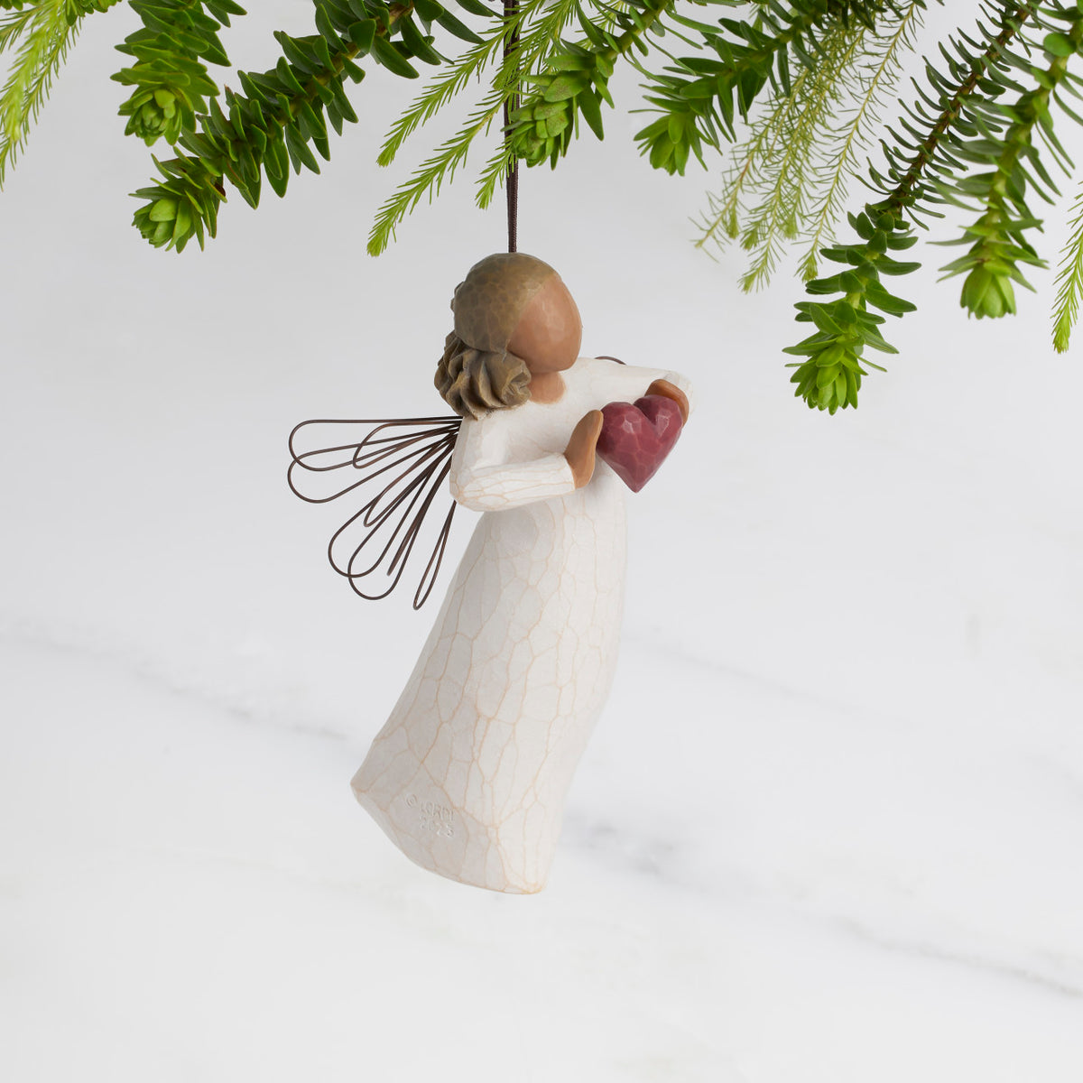 Facing right: Darker-skin Angel with wire wings holding red heart. Loop and hook attached in wings