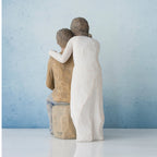 Woman figurine in white dress standing over man sitting down - all facing away from front
