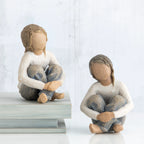 Set of two girl figurines in white shirts sitting down in blue jeans