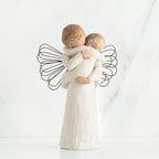 Young girl angel faceless figurine wearing white dress and has black wire wings, holding faceless baby in her arms