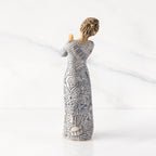 Back view: Lighter-skin figure carved with contrasting pattern of dark blue musical symbols, instruments, dancing forms