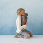 Small boy figurine in white shirt and blue jeans kneeling holding brown puppy figuirne - blue background