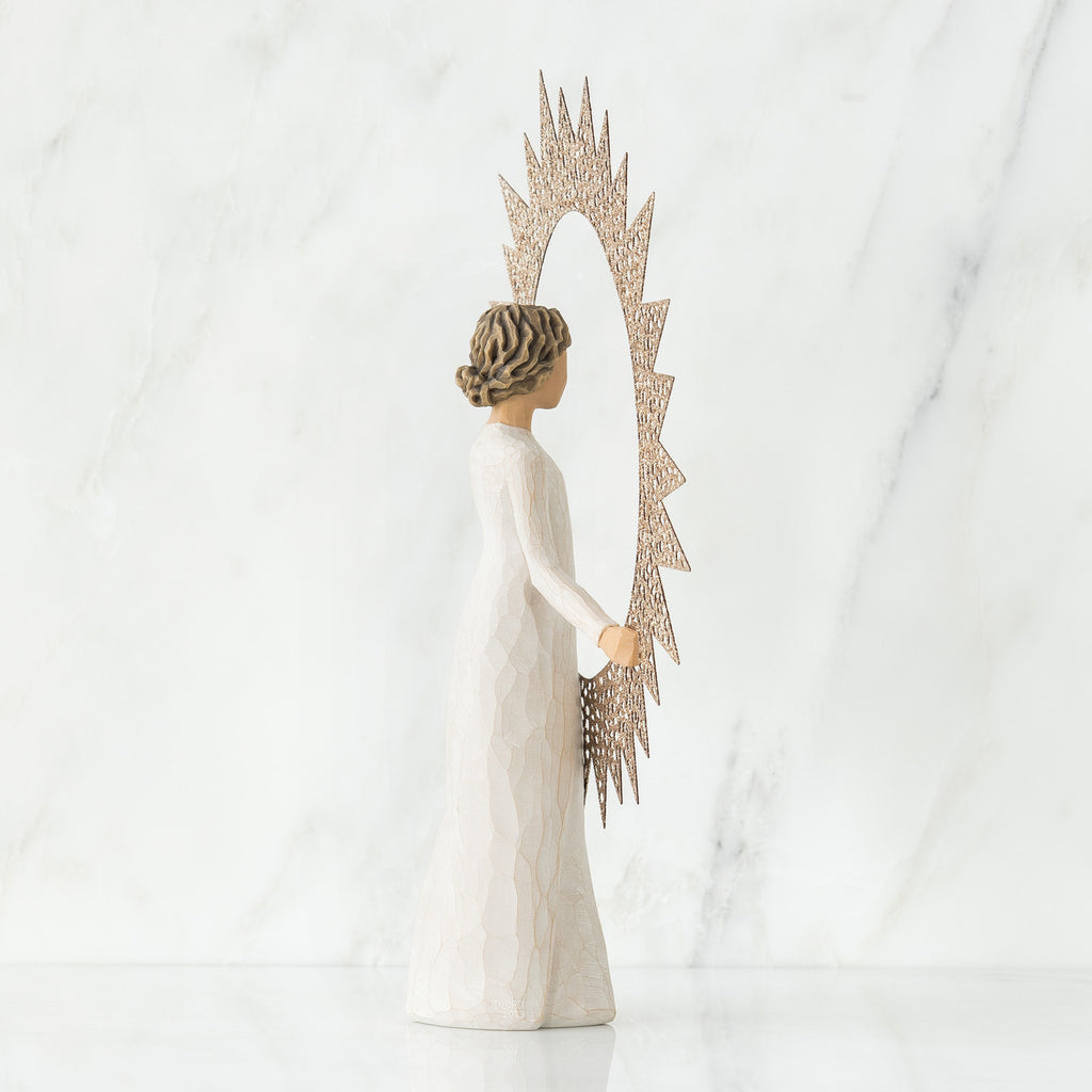 Brunette woman figurine wearing white dress facing away from the camera holding rose gold sun figurine up