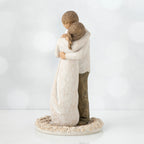 Man and woman figurine hugging one another on round cream plaque