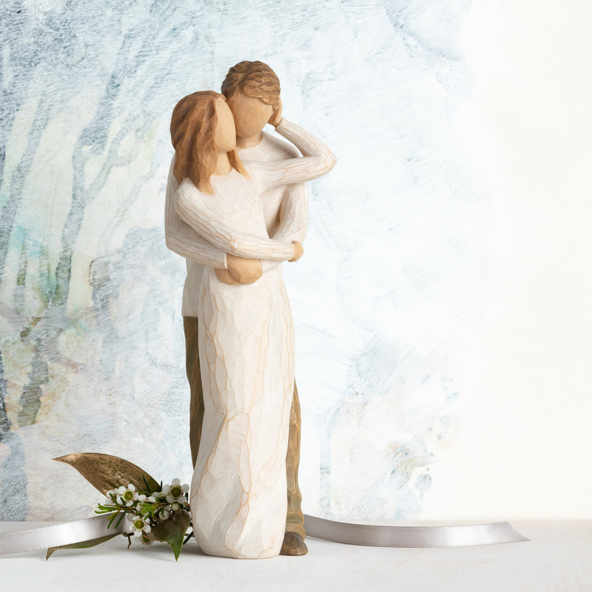 Willow Tree Together, 9”h hand-painted resin figure of couple, standing with arms around each other, dressed in neutral colors, both with lighter skin tones, in front of a blue painting