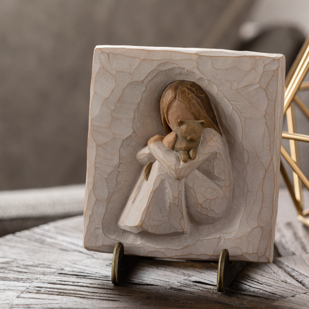 Willow Tree Comfort Plaque, 4”sq x .5”d hand-painted resin bas-relief carving of seated figure in cream dress, holding small gray cat. Plaque displayed on Plaque Stand on table