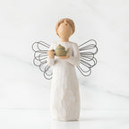Faceless angel figurine with black wire wings dressed in white holding teapot