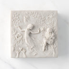 Close-up of white resin box; lid carved with figural and organic imagery