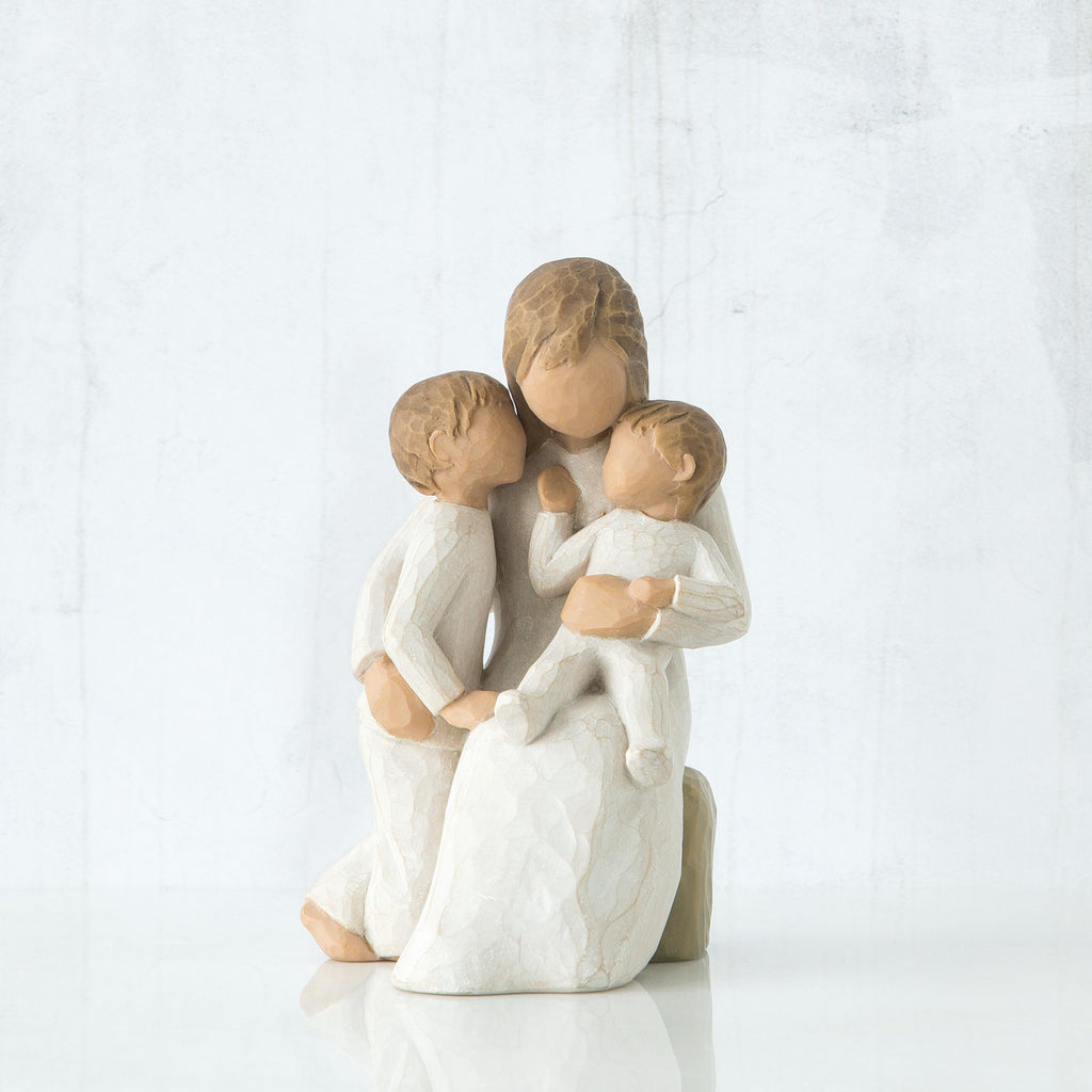 Faceless mother figurine sitting down holding two faceless children figurines in her arms