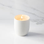 Lit filled scented candle with unglazed cream tapered cylinder vessel, sentiment written in gold inside rim, plant-based wax blend, all-cotton wick