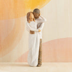 Front view of couple, standing with arms around each other. Woman has lighter skin and hair; man has darker skin and hair. Orange painted background.