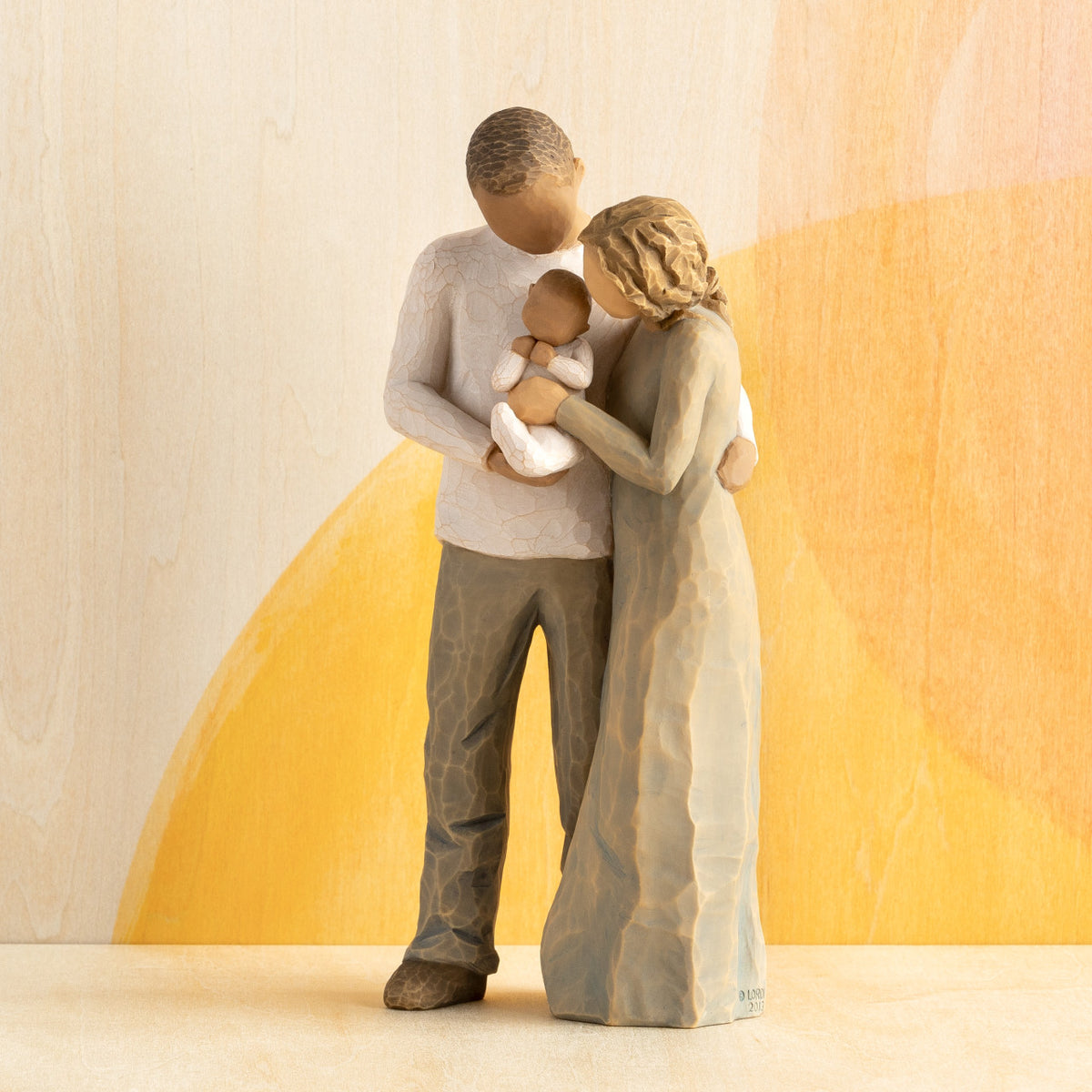 Front view of standing couple, woman has lighter skin and hair; man has darker skin and hair, holding a baby between them. Orange painted background.