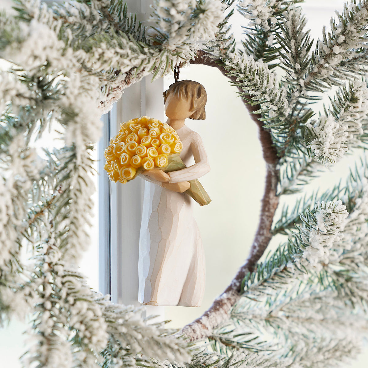 Willow Tree Good Cheer! Ornament, 4.5”h hand-painted resin figure in cream dress, holding bouquet of yellow roses, brown elastic cord, hanging inside white wreath
