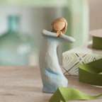 Willow Tree Journey, 5.5”h hand-painted standing resin figure in blue dress, arms raised up to face as if dancing, on wooden desk